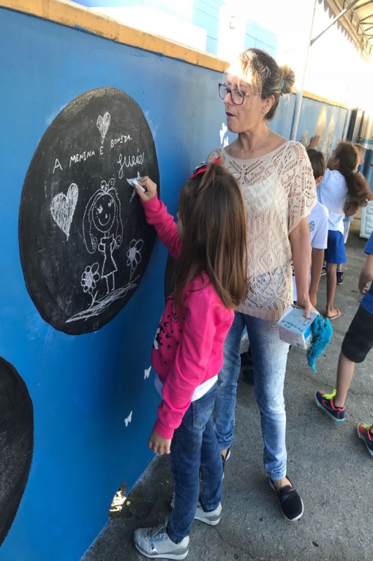 Crianças aprendem escrevendo no muro