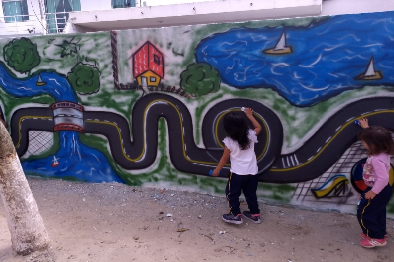Crianças se divertem com pista pintada no muro